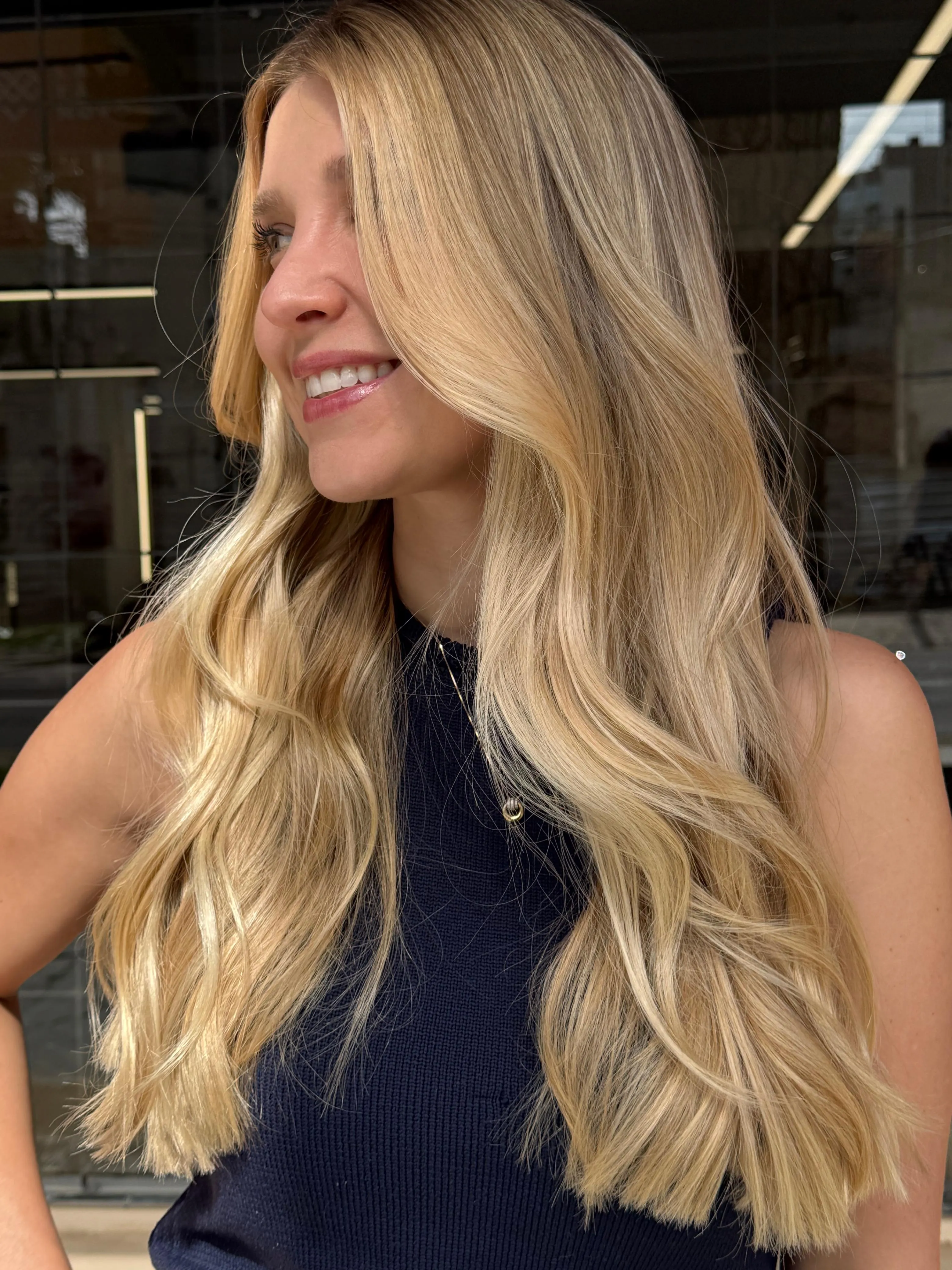 Cliente do Estúdio Auryn com mechas loiras iluminadas e acabamento natural